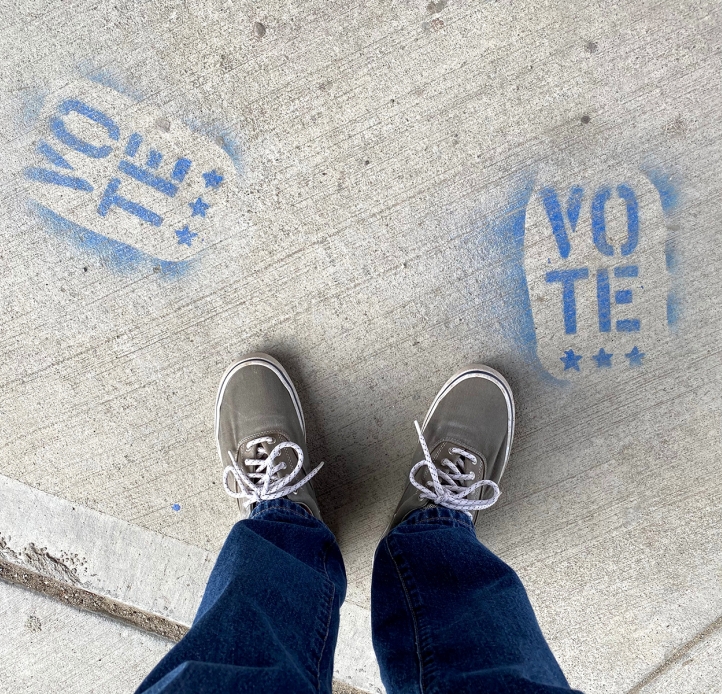 Person standing over vote stenciled on sidewalk