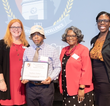 Four people posing for a picture receiving an award