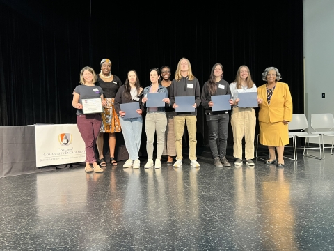 A group of people standing on stage with awards
