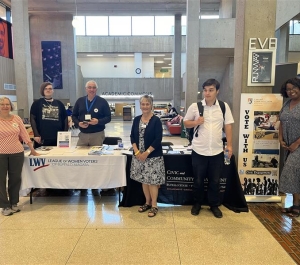 Representatives posing in front of voter education tables.