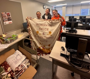 Photo of three students holding up a no-sew blanket.