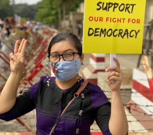 Photo of a woman holding a sign that says "Support our fight for democracy"