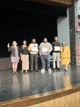 A group of people standing on stage with awards