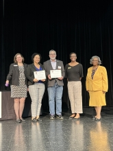 A group of people standing on stage with awards