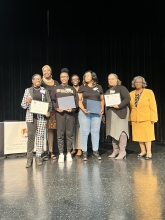 A group of people standing on stage with awards