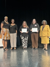 A group of people standing on stage with awards