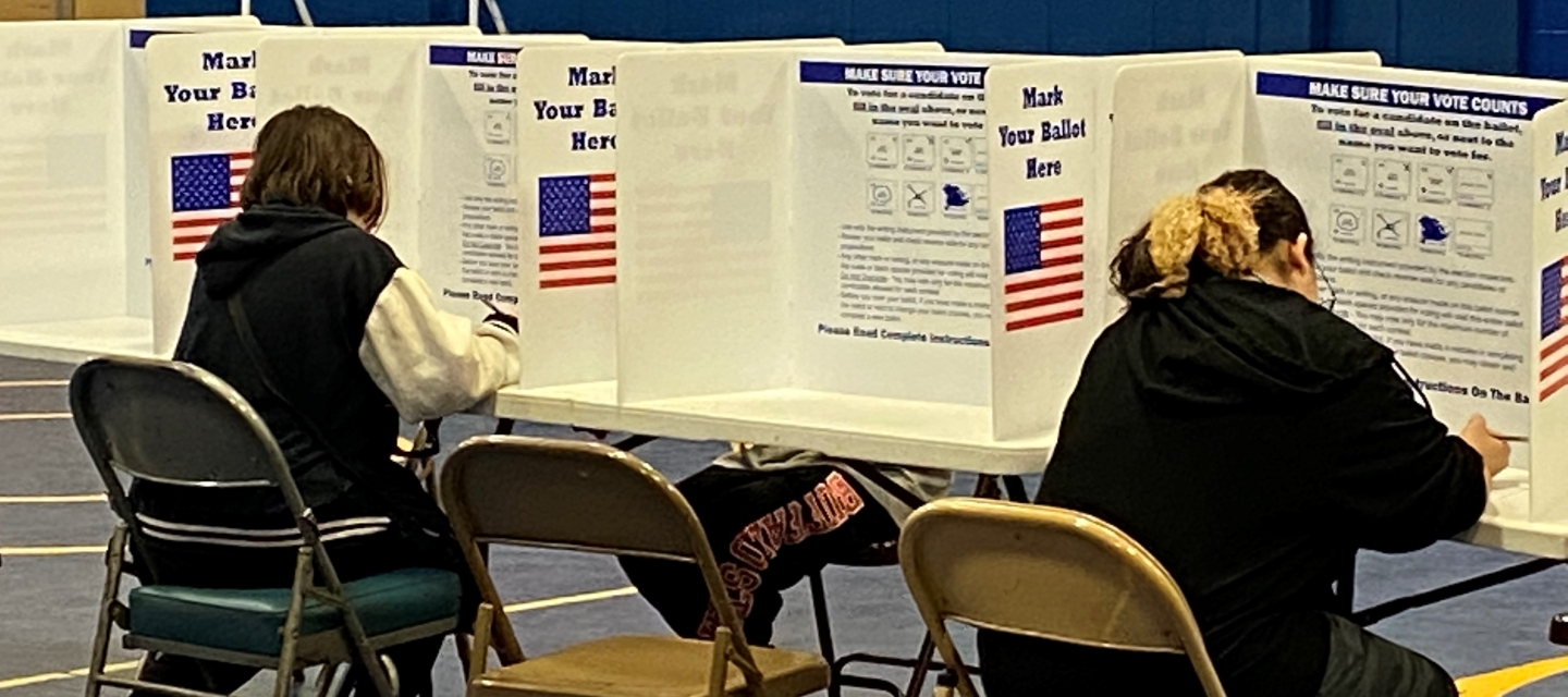 Two people sitting in chairs and voting