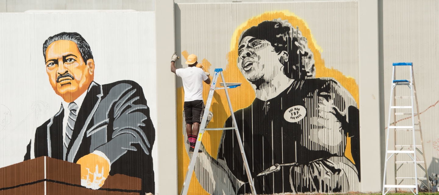 Man on ladder painting mural of Civil Rights leaders